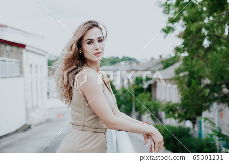 Portrait of a beautiful fashionable woman in a beige stylish dress Portrait of a beautiful fashionable woman in a beige stylish dress 65301231