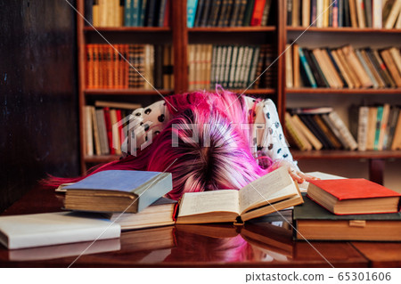 woman with pink hair asleep at a table with books in library woman with pink hair asleep at a table with books in library 65301606