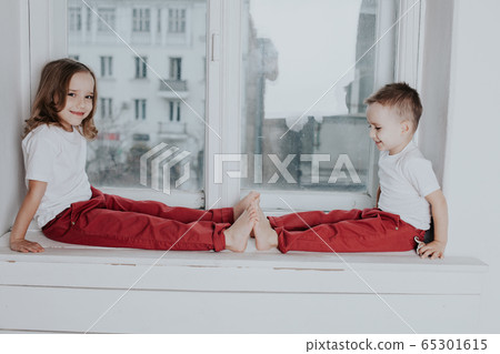 little boy and girl sit on the windowsill looking out the window little boy and girl sit on the windowsill looking out the window 65301615