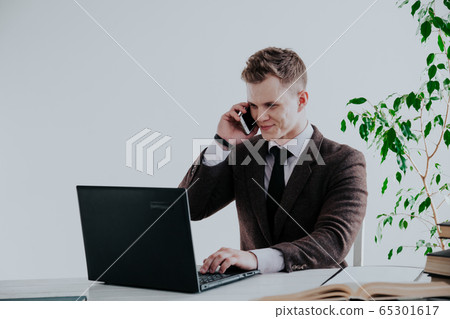 business man working at the computer and talking on the phone in the Office business man working at the computer and talking on the phone in the Office 65301617