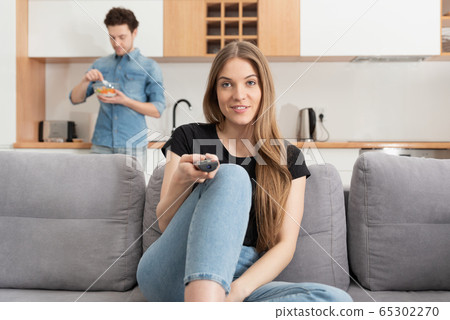 Woman watching TV on sofa in living room 65302270