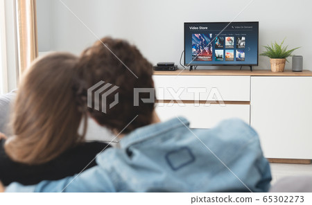 Young couple watching TV on sofa 65302273