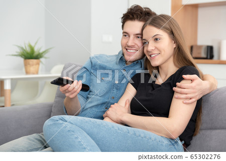 Young couple watching TV on sofa 65302276