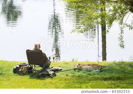 A fisherman catches fish on the river on a warm spring day. A fisherman catches fish on the river on a warm spring day. 65302553