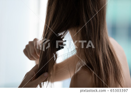 Closeup rear view woman combing hairs do morning routine Closeup rear view woman combing hairs do morning routine 65303397