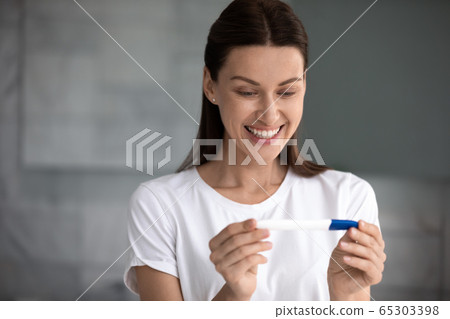 35s woman holding pregnancy test saw two stripes feels happy 65303398