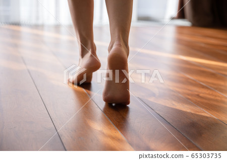 Woman walking barefoot on toes at warm floor closeup view Woman walking barefoot on toes at warm floor closeup view 65303735
