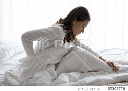 Unhealthy female woke up feels symptoms of herniated spinal disc 65303756
