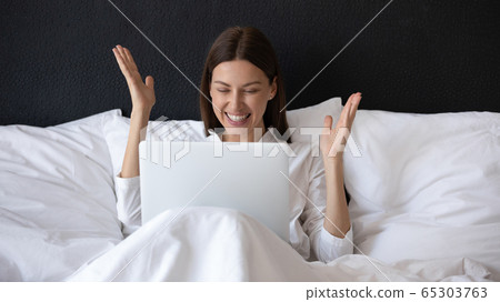 In morning woman sitting in bed with laptop feels happy In morning woman sitting in bed with laptop feels happy 65303763