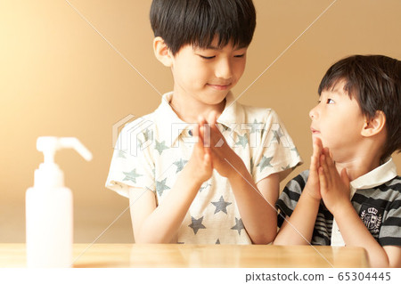Boys sanitizing hands 65304445
