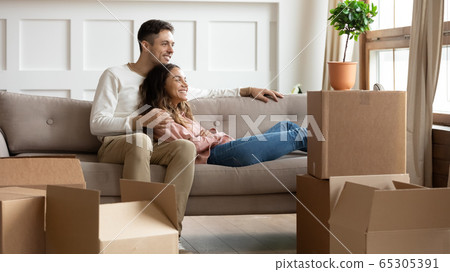 Happy young couple relaxing on couch on moving day 65305391