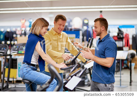 beautiful couple in sportswear store, want to buy exercise bike beautiful couple in sportswear store, want to buy exercise bike 65305509