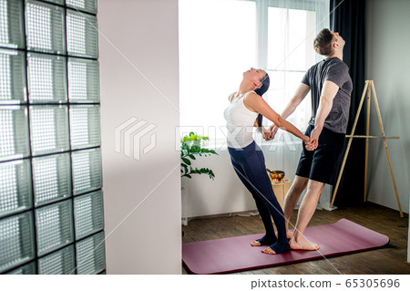 side view on caucasian fitness couple training yoga poses together 65305696