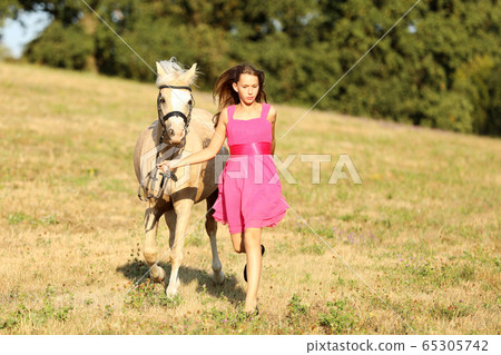 Teenage girl with pony run on meadow in late Teenage girl with pony run on meadow in late 65305742