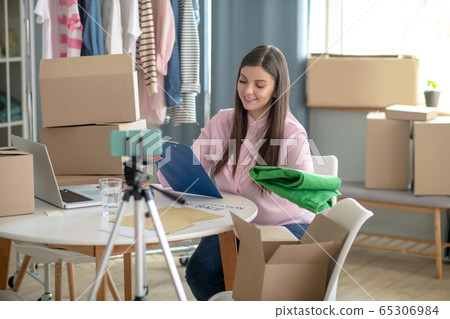 Dark-haired young woman sitting at the table during online sale Dark-haired young woman sitting at the table during online sale 65306984