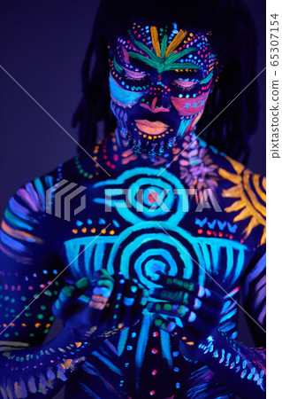 portrait of african man with ethnic pattern, neon makeup in ultraviolet light portrait of african man with ethnic pattern, neon makeup in ultraviolet light 65307154