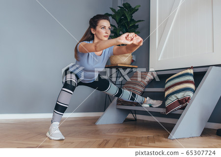 Fit woman stretching legs Lateral Lunge exercise. 65307724