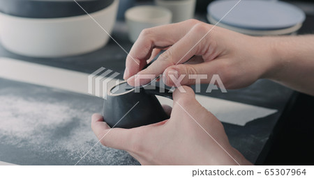 man hands polishing bottom of black ceramic cup man hands polishing bottom of black ceramic cup 65307964