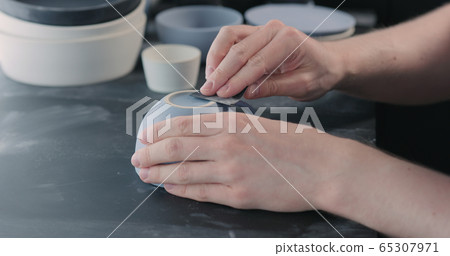 man hands polishing bottom of blue ceramic cup 65307971