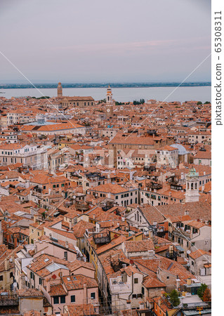 Aerial panoramic view from cathedral bell tower San Marco Campanile of old historical city centre, sea, red tiled roofs and palaces. Venice, Italy - is a popular tourist destination of Europe.  65308311