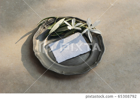 Summer wedding stationery mock-up scene. Blank business card, invitation in sunlight. Silver plate with olive branch and white carissa macrocarpa, natal plum flowers. Beige marble table background. Summer wedding stationery mock-up scene. Blank business card, invitation in sunlight. Silver plate with olive branch and white carissa macrocarpa, natal plum flowers. Beige marble table background. 65308792