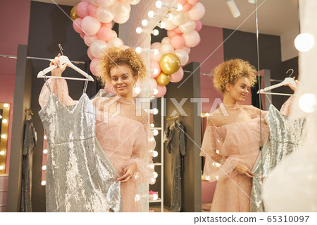 Young Woman Holding Party Dress in Boutique Young Woman Holding Party Dress in Boutique 65310097