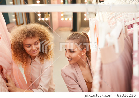 Two Young Women Choosing Dresses in Boutique 65310239