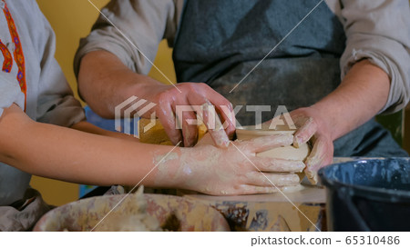 Potter showing how to work with ceramic in pottery studio 65310486