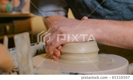 Professional male potter working with clay on potter's wheel Professional male potter working with clay on potter's wheel 65310507
