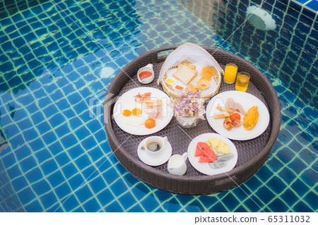Breakfast set floating around swimming pool Breakfast set floating around swimming pool 65311032