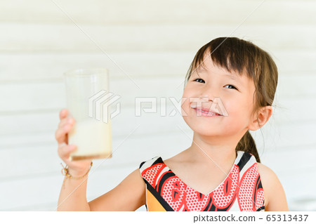 Cute smiling girl with a glass of milk ,little girl drinking milk and leaving a mustache 65313437