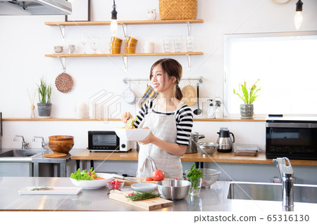 A young woman who cooks food in the kitchen 65316130