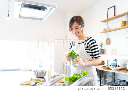 A young woman who cooks food in the kitchen 65316132