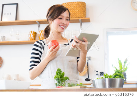 邊看著平板電腦邊做飯的年輕女子 邊看著平板電腦邊做飯的年輕女子 65316376