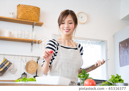 邊看著平板電腦邊做飯的年輕女子 邊看著平板電腦邊做飯的年輕女子 65316377