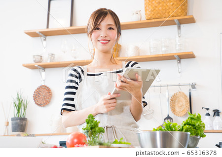 邊看著平板電腦邊做飯的年輕女子 邊看著平板電腦邊做飯的年輕女子 65316378