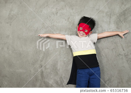 The boy smiling dressed up in superhero costume, he pretends to open arms in the studio for the educational and development concepts of young children. The boy smiling dressed up in superhero costume, he pretends to open arms in the studio for the educational and development concepts of young children. 65316736