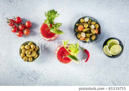 Bloody Mary cocktail with tomato juice, lime and celery, with pickles and olives, shot from above with a place for text 65319755