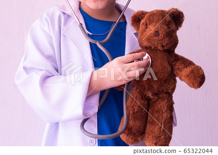 Asian girl playing doctor and listening teddy bear Asian girl playing doctor and listening teddy bear 65322044