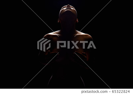 Nude Woman silhouette under light in the dark 65322824