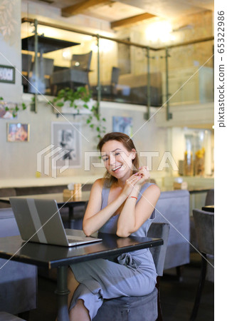 Young successful woman sitting at cafe and surfing internet by laptop. Young successful woman sitting at cafe and surfing internet by laptop. 65322986