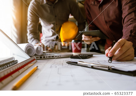 Creative architect projecting on the big drawings in the dark loft office or cafe in morning light Creative architect projecting on the big drawings in the dark loft office or cafe in morning light 65323377
