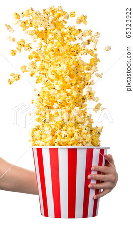 Woman hand holding striped bucket with flying popcorn isolated on white 65323922