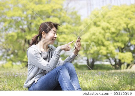 Middle woman looking at smartphone Middle woman looking at smartphone 65325599