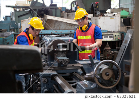 Asian factory engineer wearing yellow hard hat and 65325621