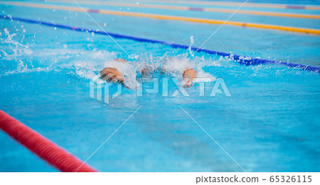Athletic man swimming in butterfly style in the swimming pool with clear blue water. Athletic man swimming in butterfly style in the swimming pool with clear blue water. 65326115