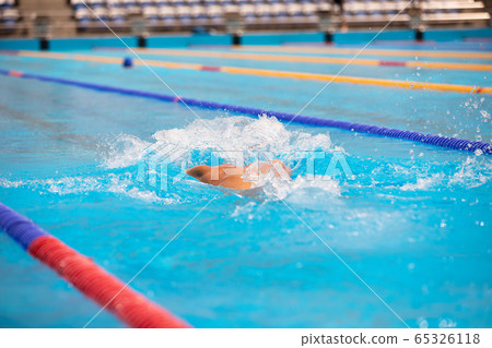Athletic man swimming in butterfly style in the swimming pool with clear blue water. 65326118