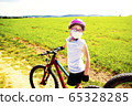 Sport and quarantine. 9 years biker girl in a mask amidst of the fields in the sunny day 65328285