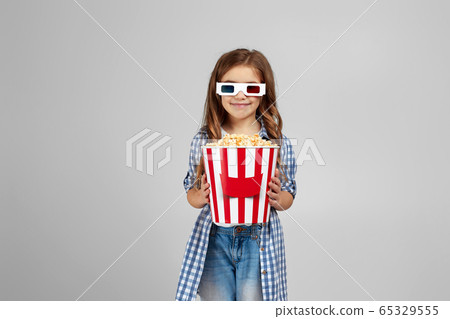 child girl wearing red-blue 3d glasses and eating popcorn child girl wearing red-blue 3d glasses and eating popcorn 65329555