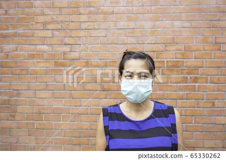 Asian women wearing a mask background brick wall. 65330262